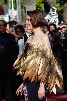 a woman in a black dress with gold wings on her shoulders