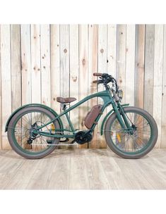 an old fashioned green bicycle parked in front of a wooden wall