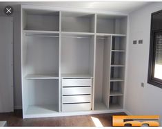 an empty room with white shelves and drawers