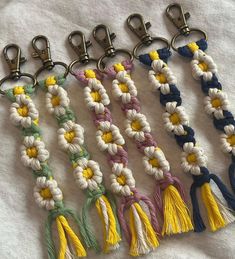 six key chains with flowers and tassels hanging from them on a white cloth