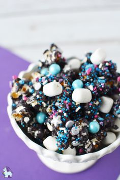 a white bowl filled with lots of sprinkles and candies on top of a purple napkin