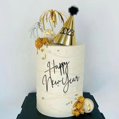 a white cake with gold decorations and a happy new year hat