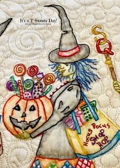 a close up of a quilt with an elephant holding a pumpkin and some candy on it