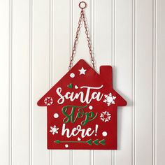 a red house sign hanging on the side of a white wall with snowflakes