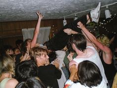 a group of people standing around each other with their arms in the air and one person on top of another