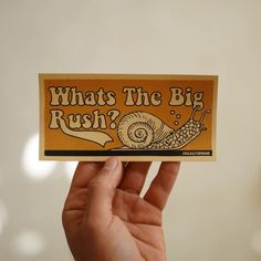 a person holding up a sticker that says, whats the big rush?