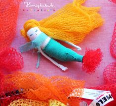 there is a small doll with orange hair on it's head next to some yarn