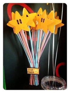 some paper stars are on top of straws in a glass vase with streamers