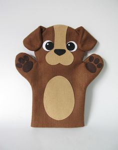 a brown and tan dog hand puppet on a white wall with one paw raised up