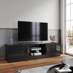 a flat screen tv sitting on top of a black entertainment center in a living room