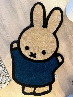 a rug with an image of a rabbit in a sweater on the floor next to a computer mouse