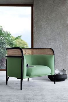 a green chair sitting in front of a window next to a potted plant on the floor