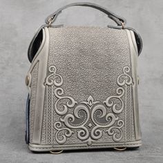 a silver handbag sitting on top of a table next to a gray wall and floor