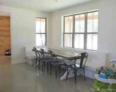 a dining room table and chairs in front of large windows