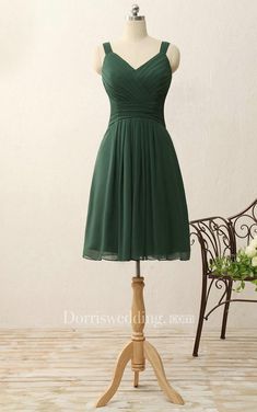 a green bridesmaid dress on a mannequin with flowers in the background