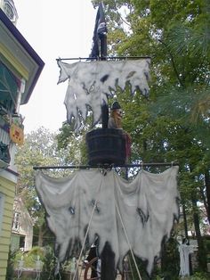 two people are on the top of a house decorated for halloween with white cloths