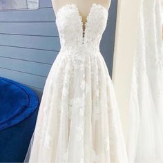 a white wedding dress on display in front of a blue chair