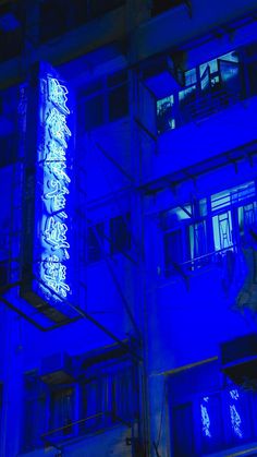 an illuminated sign on the side of a building at night with blue lights in the windows