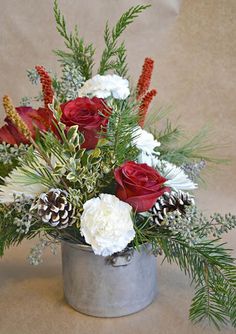 a silver vase filled with flowers and pine cones