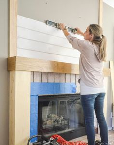 a woman is painting a fireplace with white paint