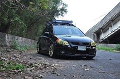 a black car parked on the side of a road next to a bridge and trees