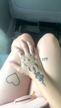 a woman with tattoos on her legs sitting in the back seat of a car and holding her hand up to her chest