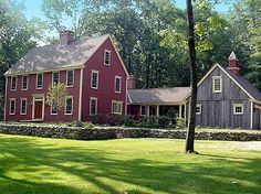 a large red house sitting in the middle of a lush green field next to trees