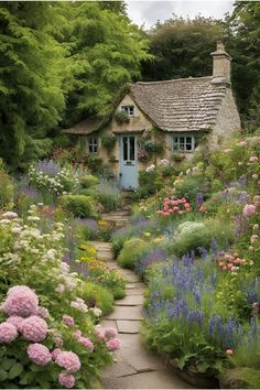 a garden with lots of flowers and a house in the background that is surrounded by trees