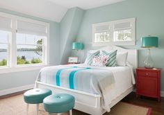 a bedroom with blue walls and white bedding has two stools in front of the bed