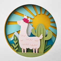 a paper cut llama standing in front of a cactus with the sun behind it