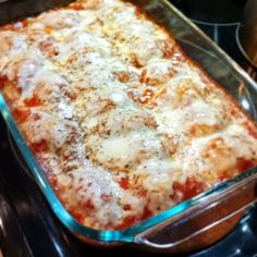 a casserole dish with cheese and sauce in it sitting on top of an oven