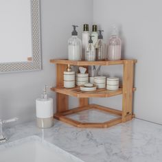 a bathroom sink with soap and lotion on the shelf next to it, in front of a mirror