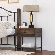 a bed with a night stand and lamp on top of it next to a wooden floor