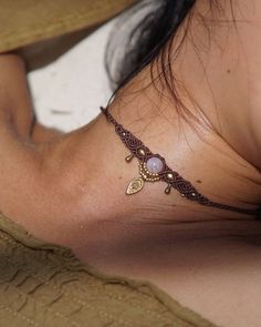 a woman with a tattoo on her neck laying down and looking at the camera while wearing a brown shirt