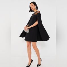 Be The Star Of The Show In The Black Estelle Dress. Full Of Effortless Elegance With A Cape-Like, Swingy A-Line Silhouette, This Darling Little Number Gets An Unexpected Yet Special Touch From The Sheer Mesh Upper That Allows You To Show Off Some Skin While Keeping It Subtle. Pair With Pumps And A Clutch For A Timeless Look That's Perfect For Party Time! Pit To Pit Measurement: 19" - Size Large Round Neckline Angled Cape Sleeves Sheer Mesh Upper Keyhole Back With Button Closure Back Zipper Swing Wedding Officiant Outfit, Cape Dress Short, Dresses With Capes, Dress With Cape Sleeves, Boss Energy, Tuckernuck Dress, African Couture, Structured Fashion, Estelle Dress