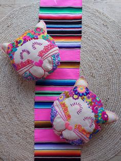 two decorative cat pillows sitting on top of a round rug next to a pink pillow