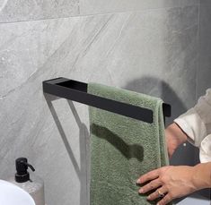 a woman is holding a green towel in front of a black holder on the wall