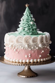 a cake decorated with icing and a christmas tree on top is sitting on a gold platter