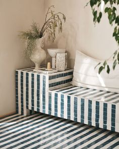 a blue and white striped bed sitting next to a plant on top of a table