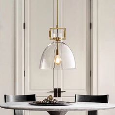 a dining room table with two chairs and a glass dome light hanging over the top