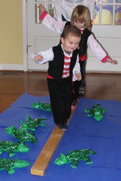 two children are jumping on the floor in front of some fake green plants and grass