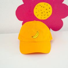 A fun hat with an embroidered banana! It has an unstructured style and antiqued brass side buckle, giving this cap that perfect, casual-cool look. It's vintage cool with six panels and with a pre-curved bill. Made from 100% cotton chino fabric. One size fits most. Embroidered in SF! Adjustable Curved Brim Fun Dad Hat, Trendy Yellow Baseball Cap With Visor, Trendy Yellow Visor Baseball Cap, Retro Adjustable Dad Hat With Curved Visor, Trendy Adjustable Yellow Dad Hat, Fun Adjustable Baseball Cap For Everyday Wear, Trendy Yellow Snapback Dad Hat, Trendy Adjustable Curved Visor Hat, Everyday Fun Hats With Curved Brim