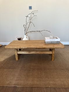 a wooden table sitting on top of a rug next to a vase with flowers in it