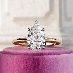 a close up of a ring with a diamond on it and a pink box in the background