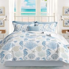 a bed with blue and white bedspread in front of a large window overlooking the ocean