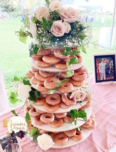 a large stack of doughnuts sitting on top of a pink table cloth covered table