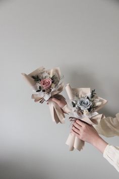 two bridesmaids holding bouquets of flowers in their hands on a gray background