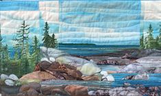 a quilted wall hanging with rocks and water