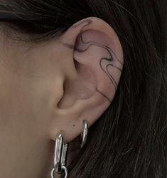 a close up of a person's ear with tattoos on it