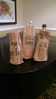 three wine bottles wrapped in brown paper sitting on top of a black table with writing on them